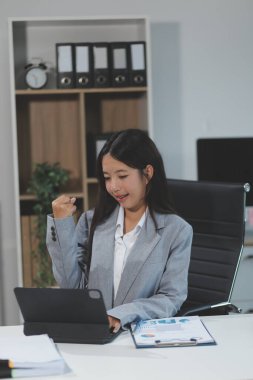 Asyalı iş kadını dizüstü bilgisayar kullanıyor ve ofiste hesap makinesi ile çalışıyor, mali raporu, iş planı yatırımını, mali analiz konseptini analiz etmeyi planlıyor..