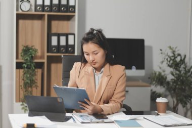 Asyalı iş kadını dizüstü bilgisayar kullanıyor ve ofiste hesap makinesi ile çalışıyor, mali raporu, iş planı yatırımını, mali analiz konseptini analiz etmeyi planlıyor..
