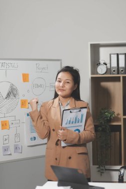 Asyalı iş kadını dizüstü bilgisayar kullanıyor ve ofiste hesap makinesi ile çalışıyor, mali raporu, iş planı yatırımını, mali analiz konseptini analiz etmeyi planlıyor..