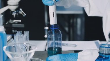 Laboratuvarda koruyucu eldivenleri ve matarası olan bilim adamı..