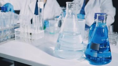 Laboratuvar çalışanı elinde kimyasal sıvıyla test tüpü tutuyor.