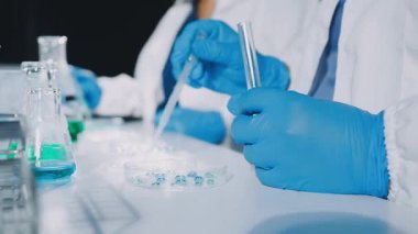 Laboratuvarda çalışan koruyucu eldivenli bilim adamı.