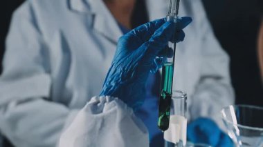 Koruyucu eldivenler ve bardaklarda sıvı tutan bilim adamları.