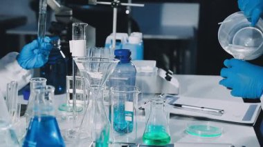 Laboratuvar asistanı elinde sıvı olan bir test tüpü tutuyor.