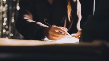 Siyah ceketli genç bir kız masaya oturur ve bir deftere yazar.