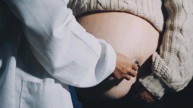 Hamile bir kadın ellerini sırtında gezdiriyor.