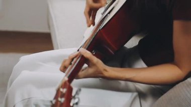 Kadın akustik gitar çalıyor.