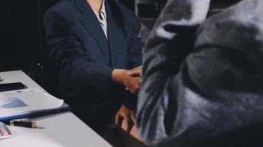 Modern bir ofiste iş adamı ortağının elini sıkıyor.