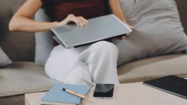 Genç kadın evde otururken dizüstü bilgisayar kullanıyor.