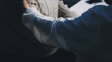 Yakından. Beyaz bir buket çiçek tutan iki adamın elleri.