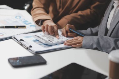 Hesap makinesi ve dizüstü bilgisayarı kullanarak ahşap masa, vergi, muhasebe, istatistik ve analitik araştırma konseptine matematik finansmanı sağlayan İş kadını kapat