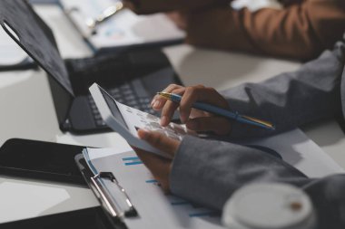 Hesap makinesi ve dizüstü bilgisayarı kullanarak ahşap masa, vergi, muhasebe, istatistik ve analitik araştırma konseptine matematik finansmanı sağlayan İş kadını kapat