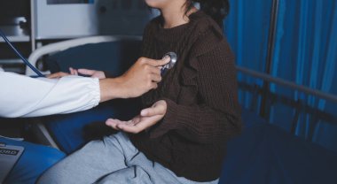 Ev bakımı hemşiresi ve yaşlılar kardiyoloji sağlık hizmetleri. Genç İspanyol kadın doktor hemşirenin yakın çekimleri sırasında steteskop kullanarak olgun beyaz hasta kalp atışlarını kontrol et.