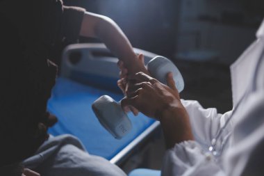 Evde dambıl kullanarak fizyoterapist eğitimi alan yaşlı bir kadın. Terapist, huzurevi egzersizlerinde yaşlı kadına yardım ediyor. Yaşlı bir hasta kollarını uzatmış halterler kullanıyor..