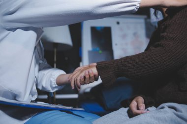 Dişi bir hemşire yaşlı bir kadını cesaretlendirmek ve teselli etmek için el ele tutuşur. Emeklilik yaşındakiler için bakım ve bakım evleri. Bakıcı yaşlı kadınlara tıbbi tavsiyelerde bulunuyor.