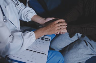 Dişi bir hemşire yaşlı bir kadını cesaretlendirmek ve teselli etmek için el ele tutuşur. Emeklilik yaşındakiler için bakım ve bakım evleri. Bakıcı yaşlı kadınlara tıbbi tavsiyelerde bulunuyor.