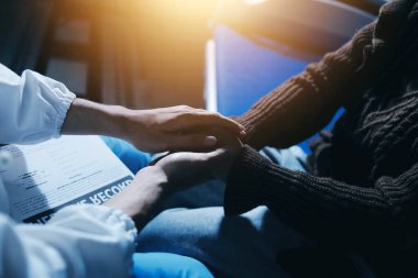 Dişi bir hemşire yaşlı bir kadını cesaretlendirmek ve teselli etmek için el ele tutuşur. Emeklilik yaşındakiler için bakım ve bakım evleri. Bakıcı yaşlı kadınlara tıbbi tavsiyelerde bulunuyor.