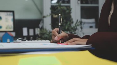 young female designer writing on a paper with pen in her workplace in a modern office.