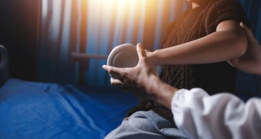 Evde dambıl kullanarak fizyoterapist eğitimi alan yaşlı bir kadın. Terapist, huzurevi egzersizlerinde yaşlı kadına yardım ediyor. Yaşlı bir hasta kollarını uzatmış halterler kullanıyor..