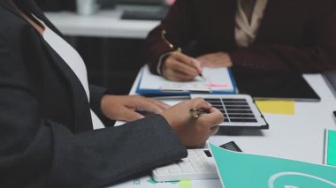 close up of businesswoman working on laptop and writing in notebook
