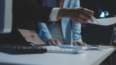 close up of businessmen hands holding documents and pointing at screen on computer keyboard