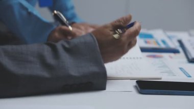 close - up of businessman writing notes in notebook on workplace in office