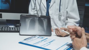 male doctor showing x - ray scan to his patient in clinic
