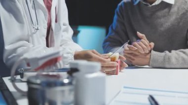 Gastroenterolog klinikteki hastayı inceliyor, insan mide modeline odaklanıyor.