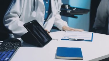 Gastroenterolog klinikteki hastayı inceliyor, insan mide modeline odaklanıyor.