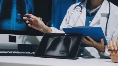 Gastroenterolog klinikteki hastayı inceliyor, insan mide modeline odaklanıyor.