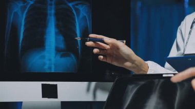 Gastroenterolog klinikteki hastayı inceliyor, insan mide modeline odaklanıyor.