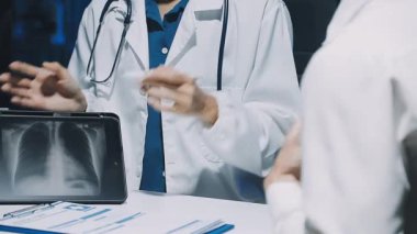 Gastroenterolog klinikteki hastayı inceliyor, insan mide modeline odaklanıyor.