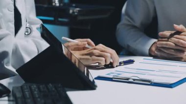 Gastroenterolog klinikteki hastayı inceliyor, insan mide modeline odaklanıyor.