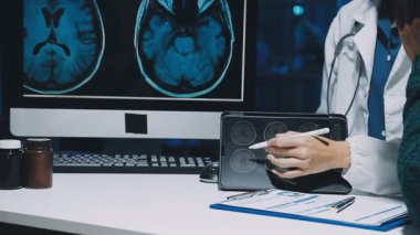 Gastroenterolog klinikteki hastayı inceliyor, insan mide modeline odaklanıyor.