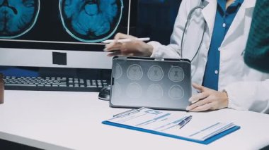 Gastroenterolog klinikteki hastayı inceliyor, insan mide modeline odaklanıyor.