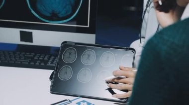 Gastroenterolog klinikteki hastayı inceliyor, insan mide modeline odaklanıyor.