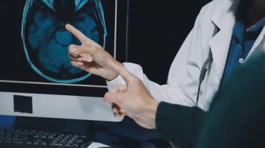 Gastroenterolog klinikteki hastayı inceliyor, insan mide modeline odaklanıyor.