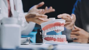 Diş hekimi, diş macunu ve dişçi muayenehanesindeki ayna aletini kullanarak hastaya diş hastalıkları tedavisini gösteriyor ve açıklıyor. Sağlık hizmetleri kavramı.