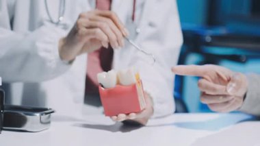 Diş hekimi, diş macunu ve dişçi muayenehanesindeki ayna aletini kullanarak hastaya diş hastalıkları tedavisini gösteriyor ve açıklıyor. Sağlık hizmetleri kavramı.