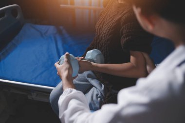 Evde dambıl kullanarak fizyoterapist eğitimi alan yaşlı bir kadın. Terapist, huzurevi egzersizlerinde yaşlı kadına yardım ediyor. Yaşlı bir hasta kollarını uzatmış halterler kullanıyor..