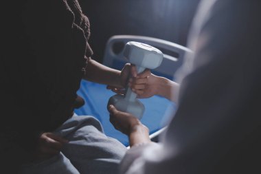 Evde dambıl kullanarak fizyoterapist eğitimi alan yaşlı bir kadın. Terapist, huzurevi egzersizlerinde yaşlı kadına yardım ediyor. Yaşlı bir hasta kollarını uzatmış halterler kullanıyor..