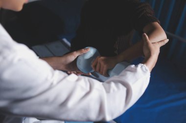 Evde dambıl kullanarak fizyoterapist eğitimi alan yaşlı bir kadın. Terapist, huzurevi egzersizlerinde yaşlı kadına yardım ediyor. Yaşlı bir hasta kollarını uzatmış halterler kullanıyor..