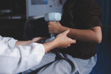 Evde dambıl kullanarak fizyoterapist eğitimi alan yaşlı bir kadın. Terapist, huzurevi egzersizlerinde yaşlı kadına yardım ediyor. Yaşlı bir hasta kollarını uzatmış halterler kullanıyor..