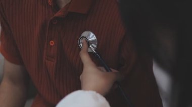 Doktor steteskop kullanıyor, kalp atışlarını kontrol ediyor, hastanedeki doktor muayenehanesinde bakım yapıyor. Hasta her yıl sağlık kontrolü yaptırmak zorundadır.