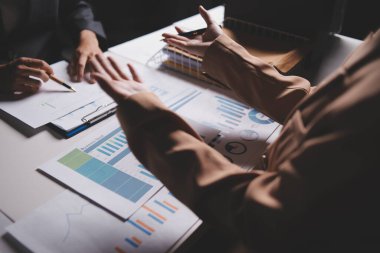 İki iş adamı toplantı odasında proje stratejisi hakkında konuşuyor. İş adamı, mali veri raporu hakkında sohbet ve tavsiyelerde bulunurken, modern işyerindeki iş arkadaşıyla proje planlamasını tartıştı.