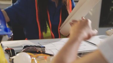 İki mimar planları analiz ediyor ve ofis ortamındaki bir inşaat projesi hakkında detaylı bir tartışmaya girişiyorlar.