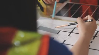 İki mimar planları analiz ediyor ve ofis ortamındaki bir inşaat projesi hakkında detaylı bir tartışmaya girişiyorlar.