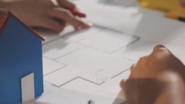 İki mimar planları analiz ediyor ve ofis ortamındaki bir inşaat projesi hakkında detaylı bir tartışmaya girişiyorlar.