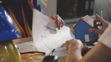 İki mimar planları analiz ediyor ve ofis ortamındaki bir inşaat projesi hakkında detaylı bir tartışmaya girişiyorlar.