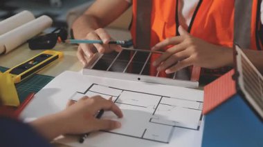 İki mimar planları analiz ediyor ve ofis ortamındaki bir inşaat projesi hakkında detaylı bir tartışmaya girişiyorlar.